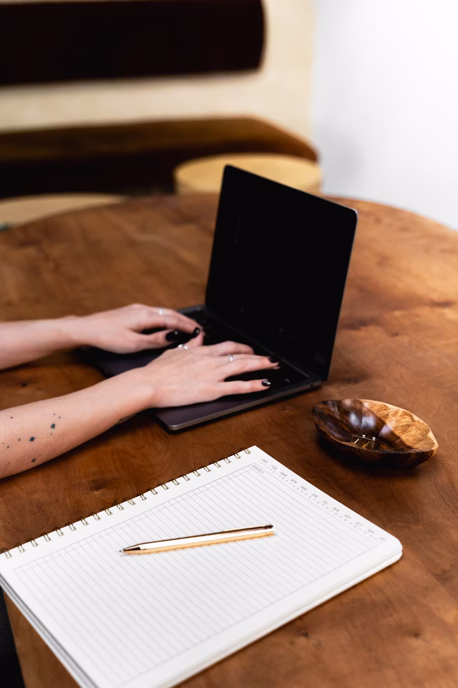 Woman typing on laptop with notebook and paper